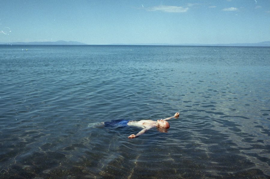 homme allongée dans l'eau qui fait la planche, image de mer en Grèce